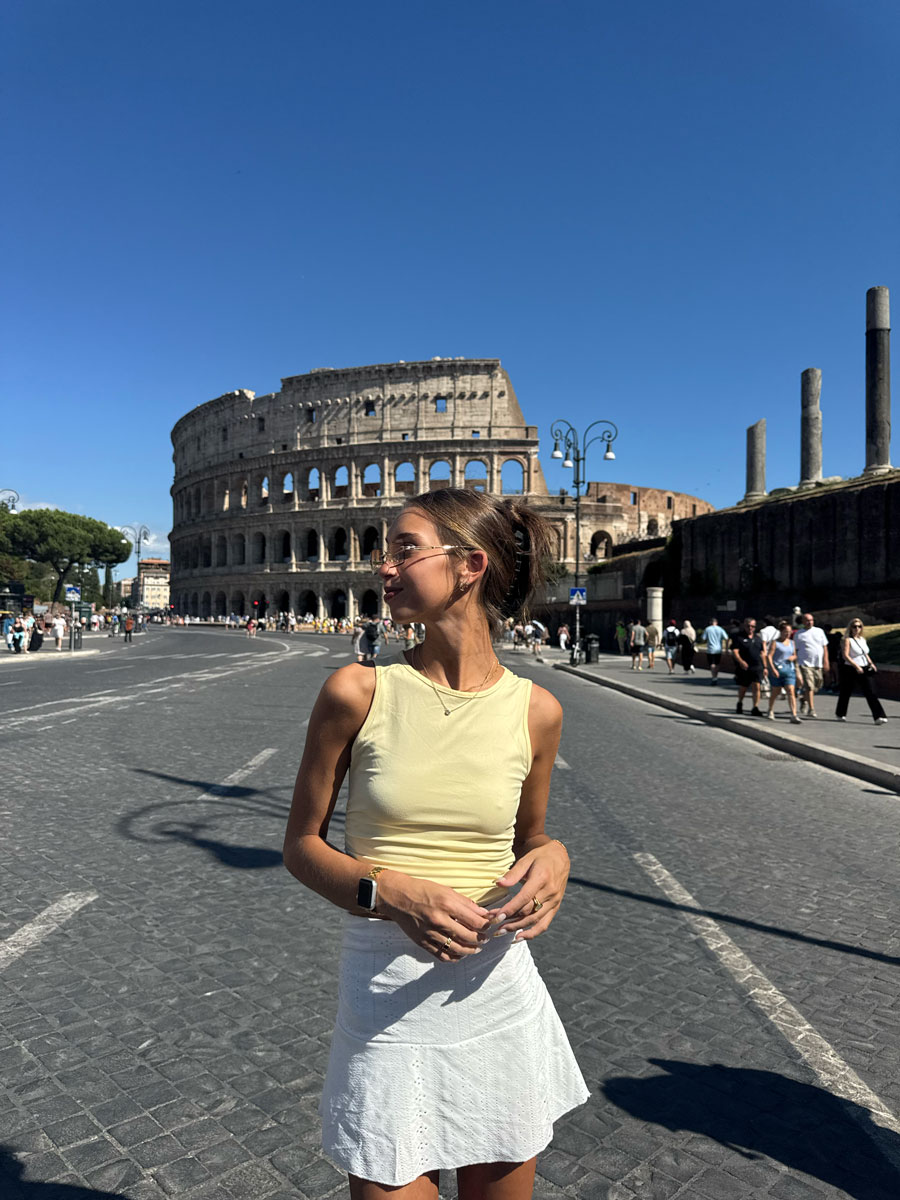 The coach is posing front of the colosseum.